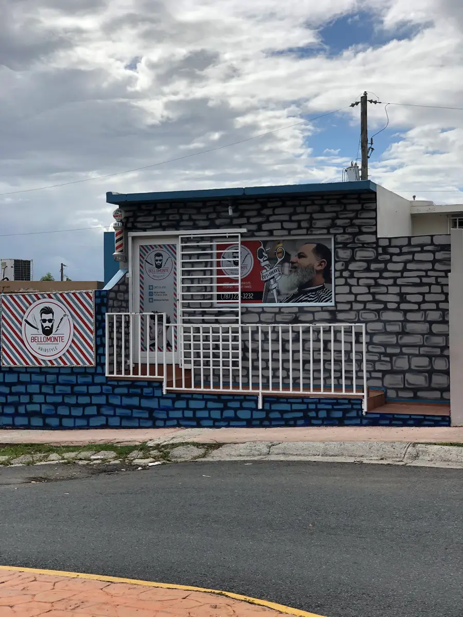 Fachada de Bello Monte Hair Style en Guaynabo, con su letrero y mural sobre una pared de piedra.