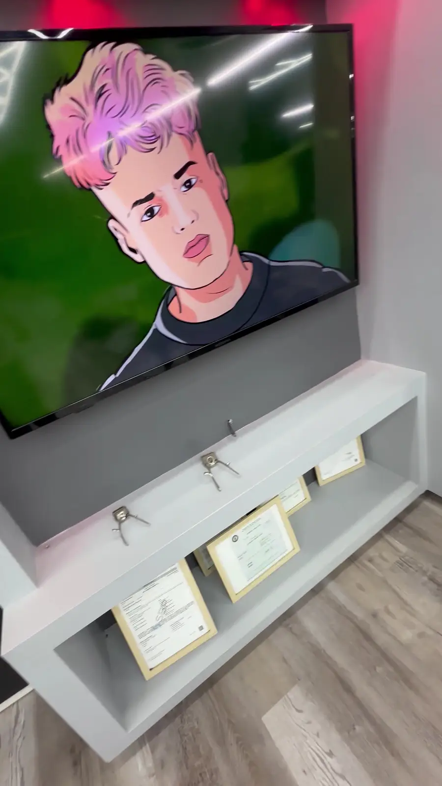 Pantalla con un dibujo de un corte de pelo y certificados enmarcados en la tablilla.